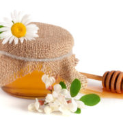 Jar of honey with flowers of acacia and chamomile isolated on wh